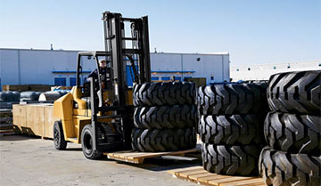 Cat diesel forklift next to stacks of large tires